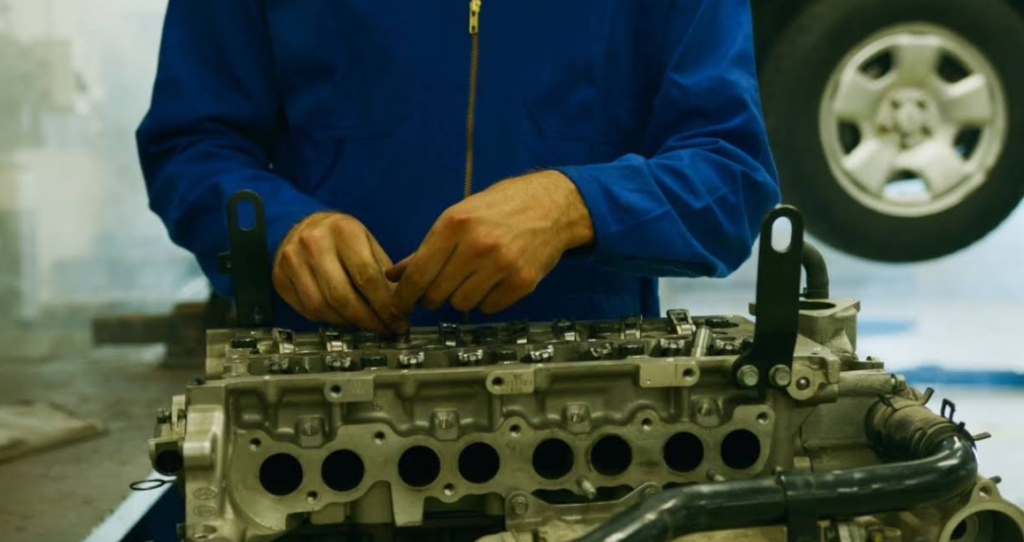 Mechanic repairing a blue outboard boat motor in a workshop.